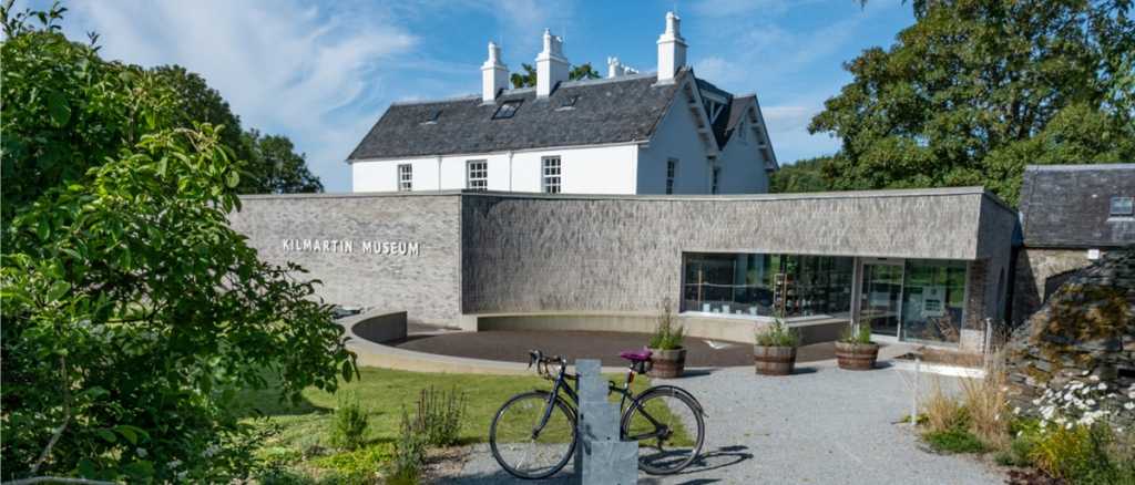 Bicycle parked at museum's entrance courtyard, comprised of a garden and curved wall