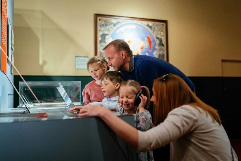 A man, woman and three children look at a display and listen to an earpiece at PK Porthcurno museum