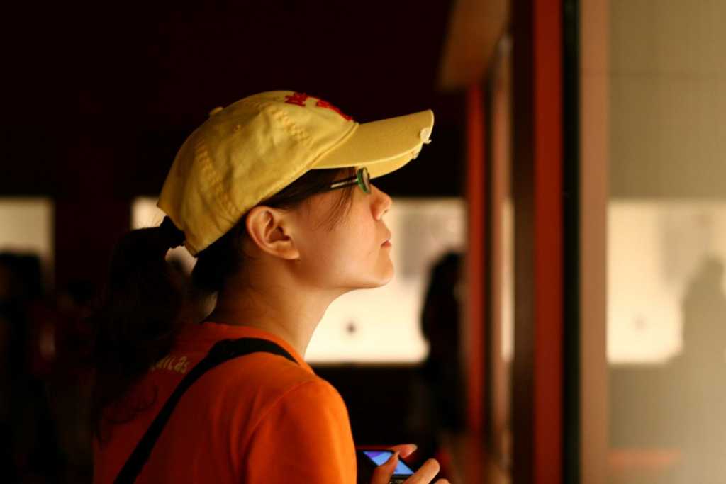 Person in a baseball cap looking at a museum display in a glass case