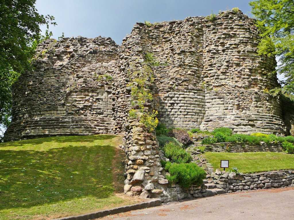 Old stone walls of Pontefract Castle surrounded by grass and trees