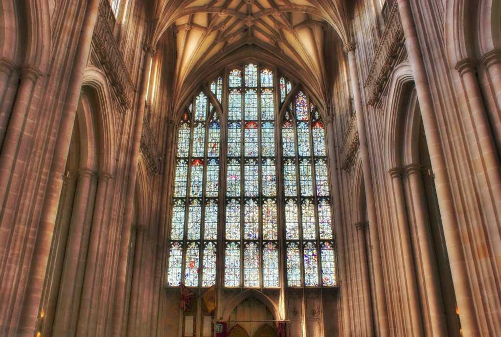 Large and intricate stained glass window inside the stone interior of Winchester Cathedral
